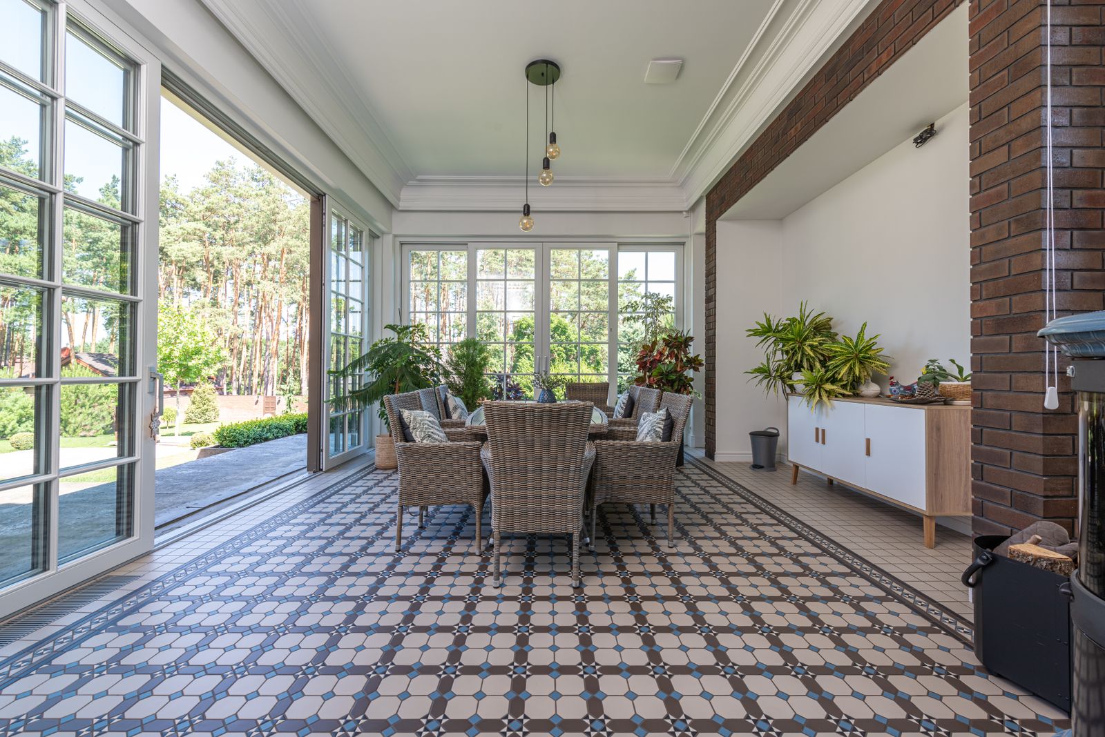 A bright sunroom lined with white-framed windows and a patterned floor.